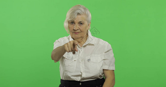 徽标ps素材一位老妇人指着镜头微笑一件白衬衫的老俏丽的祖母放置您的徽标或文本色度背景