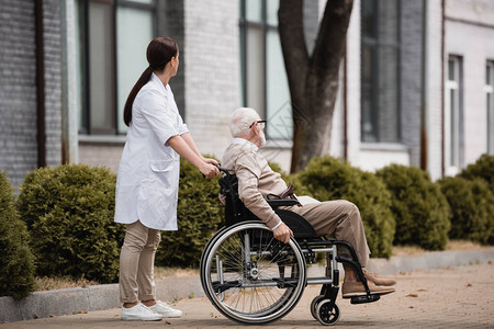 社会工作者与老年残疾男子一起在户外图片