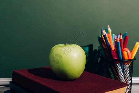 整个苹果放在笔架附近的书本上图片