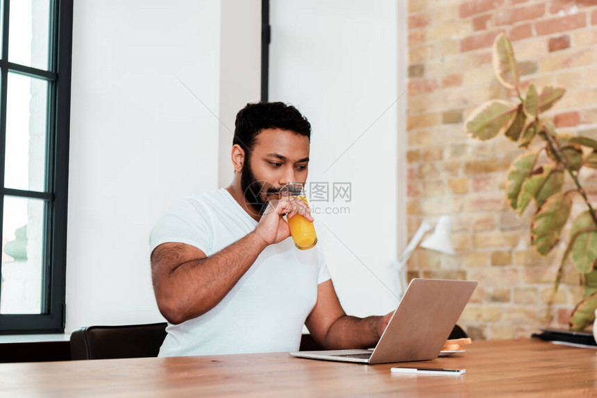 在家工作时喝橙汁的美国自由职业者图片