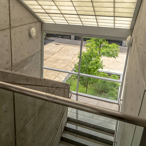 带有金属扶手和倾斜玻璃屋顶的建筑物的楼梯方形飞行透过玻璃墙可以看到铺图片