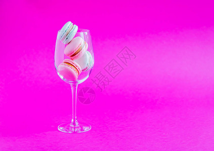 粉红色背景的玻璃杯子上的麦卡龙斯法国饼干图片
