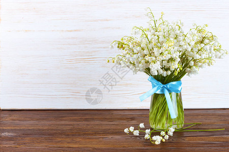 花瓶中的山谷百合花束蓝丝带以棕色和图片