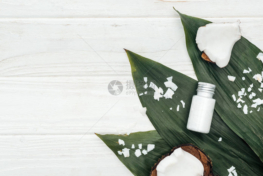 绿色棕榈叶上瓶子中的椰子美容产品图片