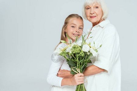 微笑的祖母拥抱孙女花束被灰色隔离图片