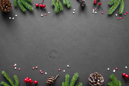 圣诞作文圣诞装饰松果冷杉树枝黑色背景上的红色浆果平躺图片