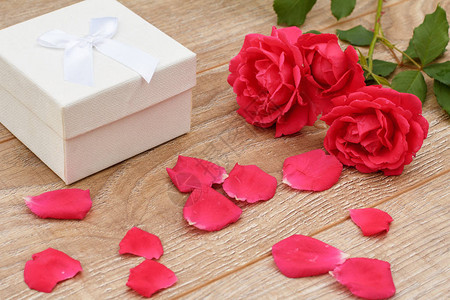 白色礼物盒玫瑰花瓣和木制背景上美丽的玫瑰假日赠送礼物的概图片