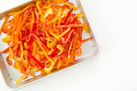 白色背景铝盘中的红色橙色和黄色甜椒片图片