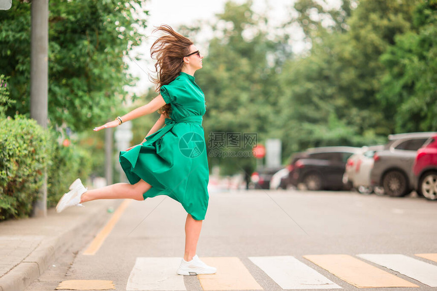 年轻女子在大城市周围走动身着绿裙子的图片