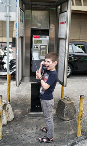 年轻的快乐兴奋的高加索男孩在澳门街上讲公用电话图片