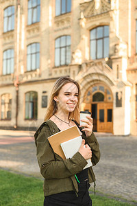 有吸引力的微笑白种人年轻女学生拿着学生书拿走大学前的咖啡大学生在校园附近享受阳光和咖背景图片