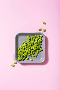 粉色背景的灰色广场上的绿色生豆子图片