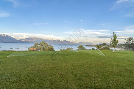 蓝湖雪山和天空风景的广大草地上喷雾者图片