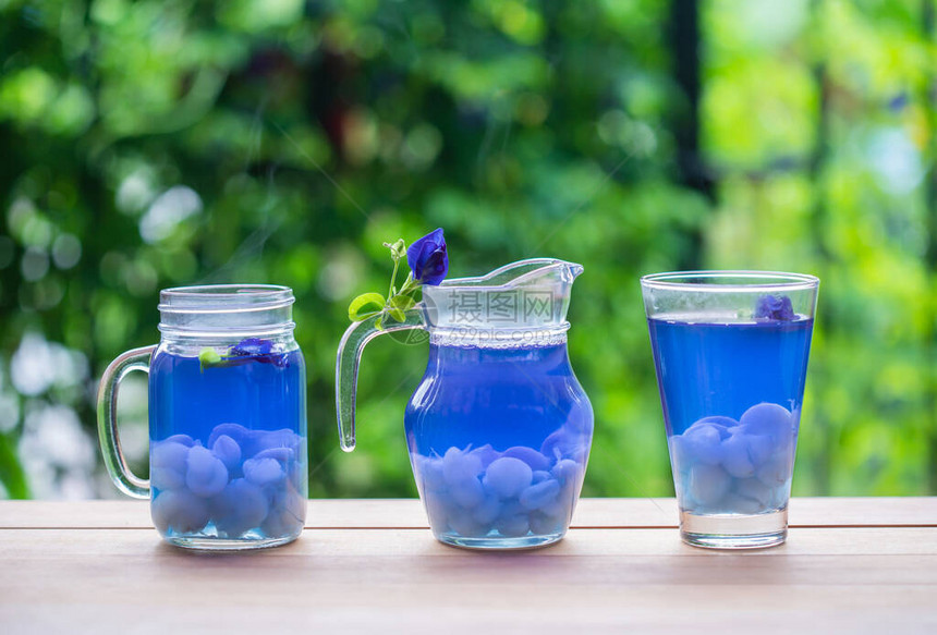 蝴蝶豌豆汁与龙眼在木桌上的玻璃杯中图片