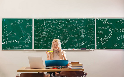 现代教师时髦在大黑板上用数学公式写作图片