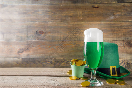 圣帕特里克节派对的传统爱尔兰酒不同的玻璃杯配绿色啤酒巧克力硬币装饰和绿色妖精帽子古朴的木质背景图片