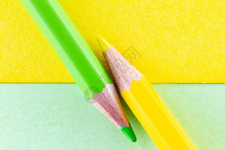 黄色和绿色的彩色铅笔在对角线排列的黄色和绿色背景色纸上极图片