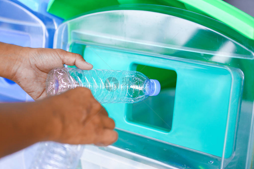 人类把空塑料瓶放进绿色垃圾桶中图片