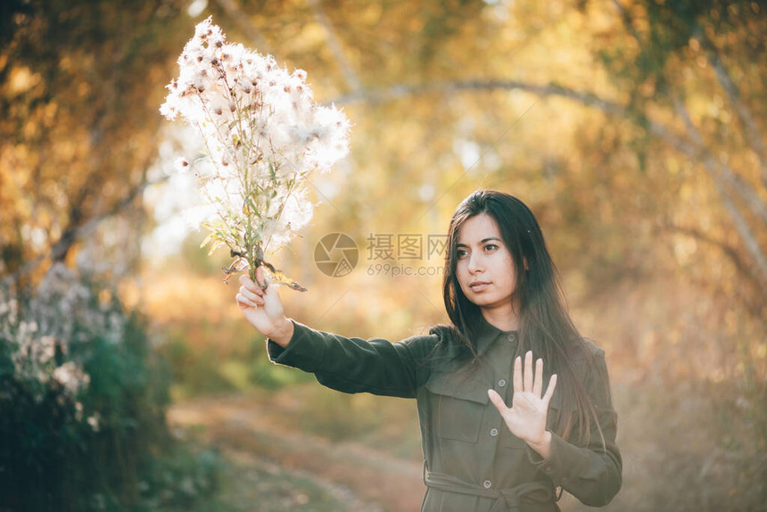 梦幻般的美丽女孩与蓟花束在金色的阳光下散景背与黄色的叶子受启发的女孩在秋天的森林里享受日落秋叶间的图片