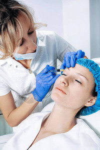 医生美容师在美容院诊所为中年女面部皮肤做紧致和抚平皱纹的面部注射程图片
