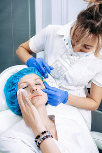 医生美容师在美容院诊所为中年女面部皮肤做紧致和抚平皱纹的面部注射程图片