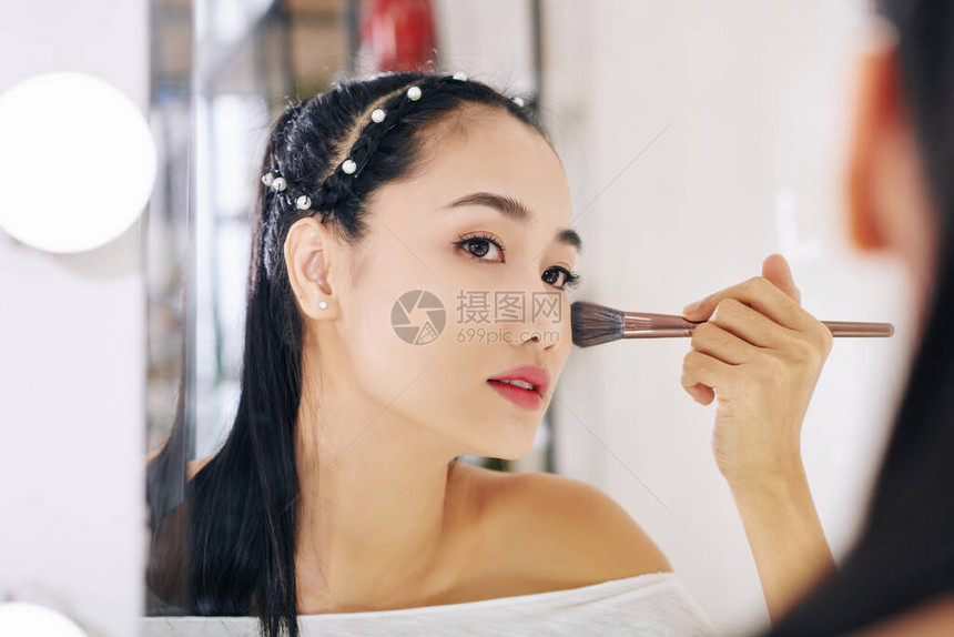 美丽的亚洲年轻女士看着镜子脸颊沾上图片
