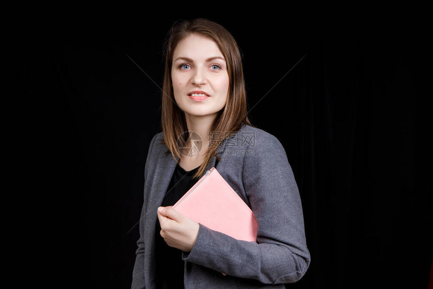 可爱的年轻女人穿着一件商业外套手里拿着一本图片