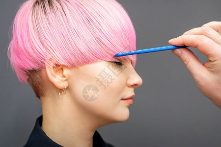 理发师检查短粉红色头发风格的年轻女用图片