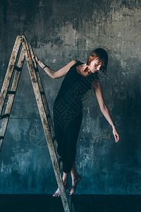 室内美容的年轻美女假扮在梯子上模特儿时尚背景图片