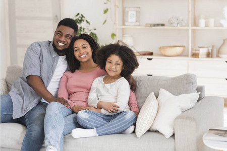 慈爱的黑人父亲母亲和小女儿在沙发上拥抱图片