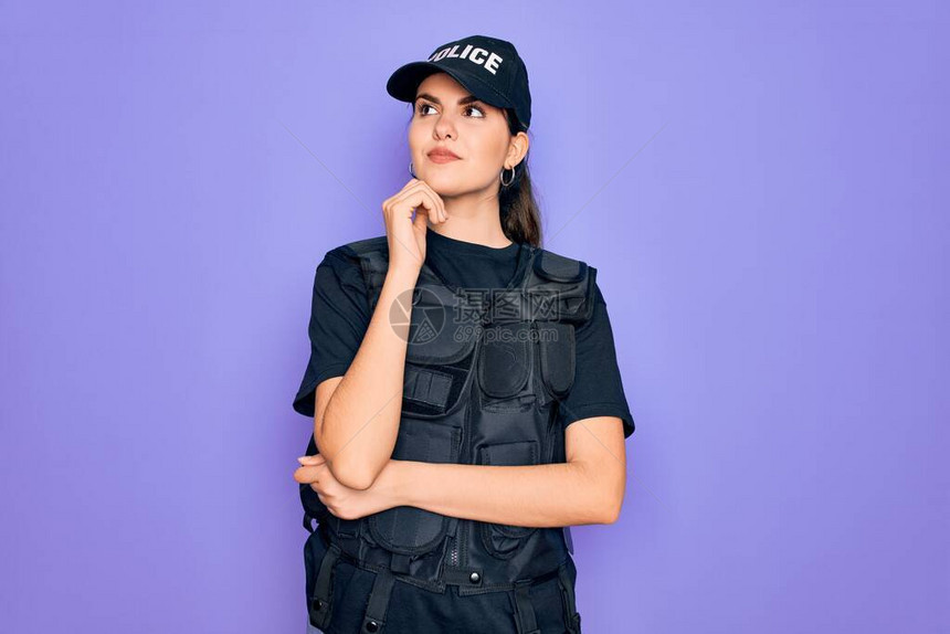 年轻的女警察穿着紫色背景的安全防弹背心制服图片