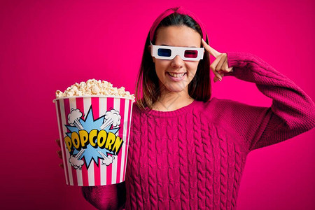 年轻漂亮的女孩用带爆米花的3D眼镜吃盒看电影图片