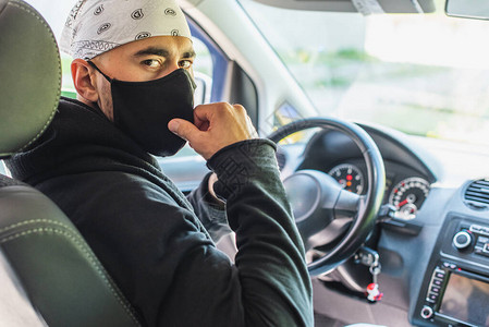 检疫概念大流行新冠一位年轻的出租车司机戴着黑色防护医用口罩图片