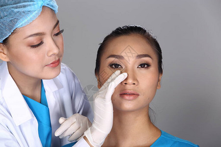 亚洲医生护士检查在整容手术和向病人注射美容化学注射器前的鼻孔结构图片