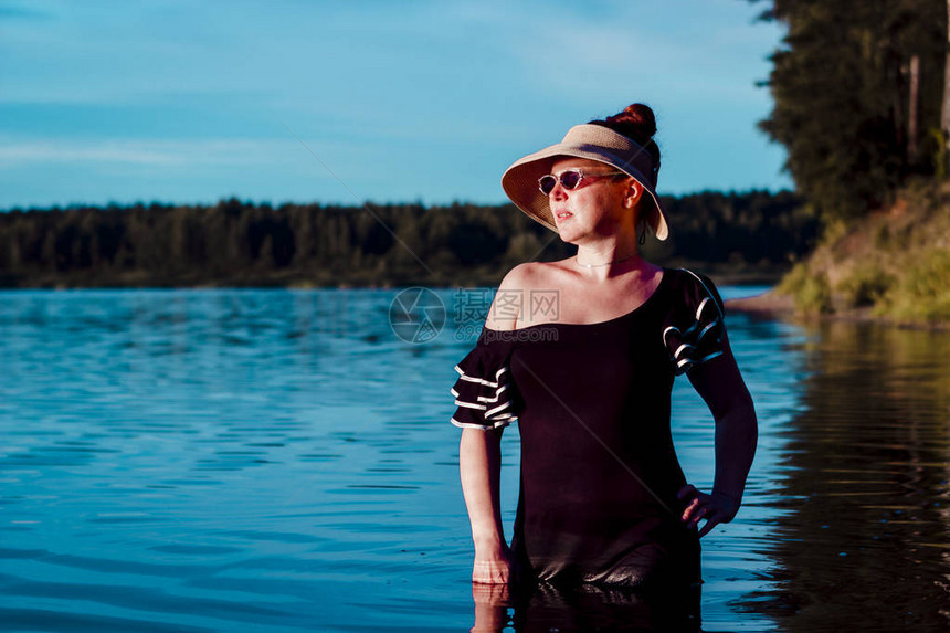 穿着草帽的女孩在湖里黑裙子湿透了水往远处看图片