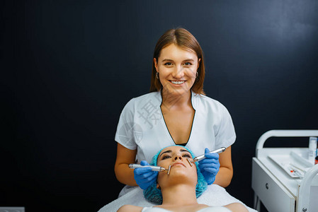 美容师在注射肉毒杆菌毒素后抚平面部在美容院的复兴程序医生和女人图片