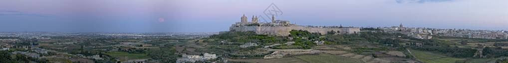 超月球在马耳他中世纪城市Mdina及其周边乡村的全景下升起图片
