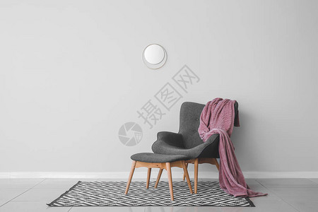时尚的扶手椅和脚凳靠近房间的轻墙图片