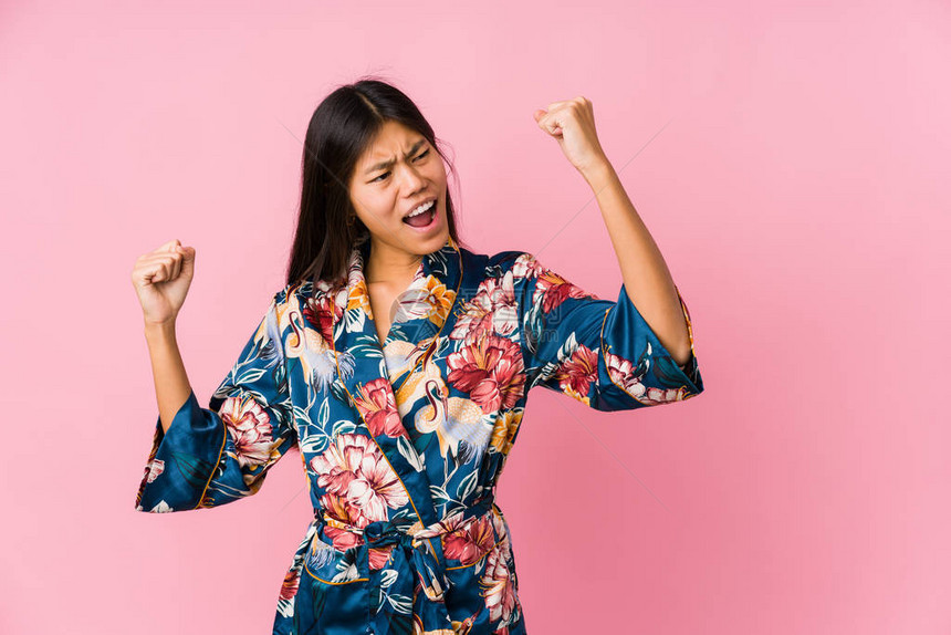 年轻的亚洲女人穿着和服睡衣在胜利后举拳图片