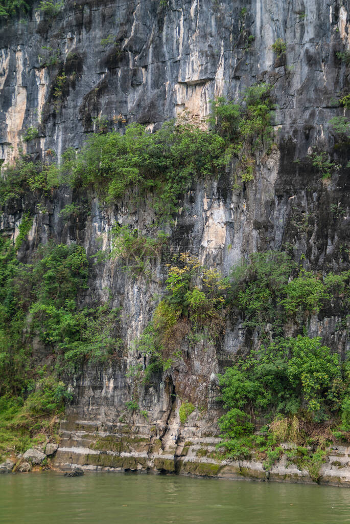 关闭绿水中垂直的喀斯特山悬崖灰褐色黑墙图片