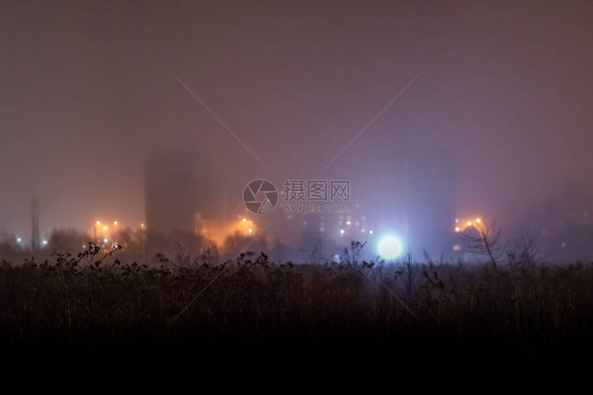 深雾的夜间压抑郊区面板高楼建筑群前的干燥暗草地图片