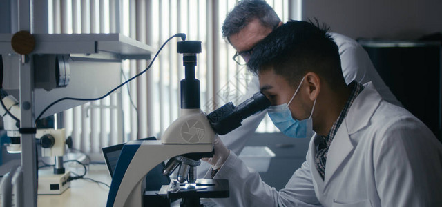 研究人员在实验室显微镜中研究样本的近图片