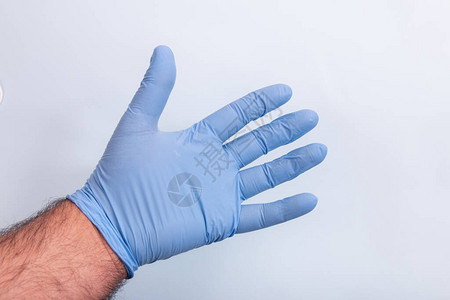 医生用蓝色的医学手套在浅蓝色的背图片