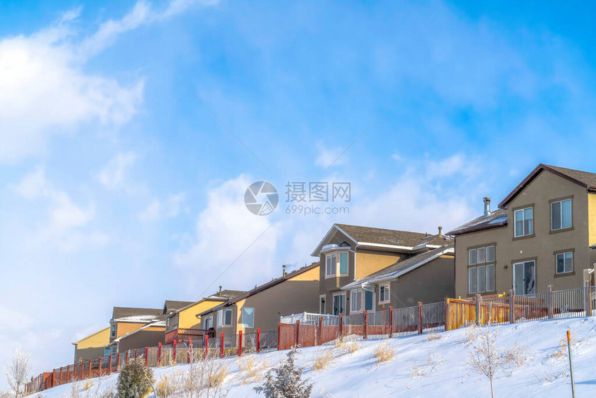 这些房屋周围都是阳光明媚的冬日雪覆盖的斜坡图片