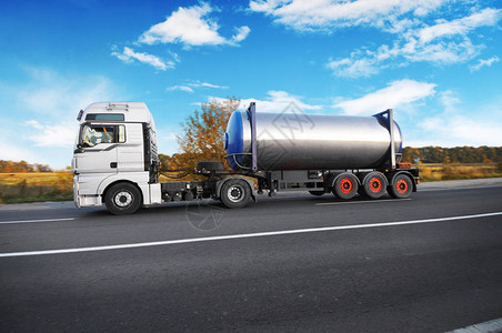 大金属油罐车载运卡车在农村公路上运输燃料图片