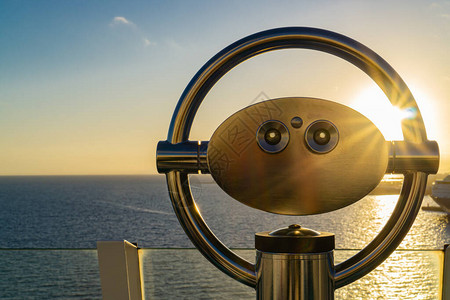 在日落时俯瞰大海的游轮上的双筒望远镜图片