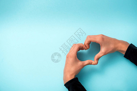 妇女用蓝色手显示心脏形状的标志并背景图片