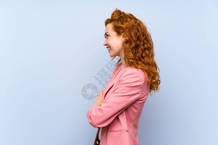 红发女人穿着孤立的蓝墙图片