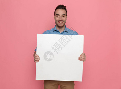 英俊的年轻随身男子拿着空白板微笑着粉图片