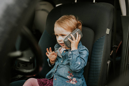 汽车座椅上的小女孩她手里拿着电话坐驾驶座汽车损坏图片